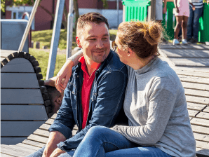 Kvinna med armen om sin arm sittande på träbänk